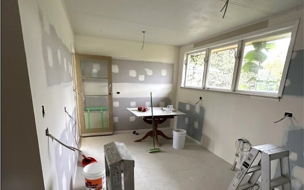 Before: kitchen stripped back to bare plasterboard, then finished with white walls, subway tiles and sage cabinetry